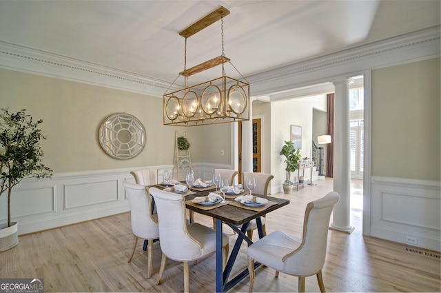 dining space with visible vents, crown molding, a wainscoted wall, decorative columns, and light wood-style flooring