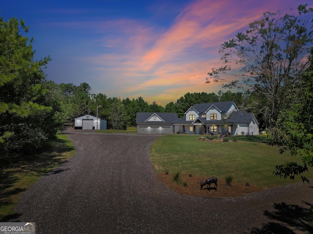 view of front of house with an outbuilding, driveway, a lawn, and a detached garage