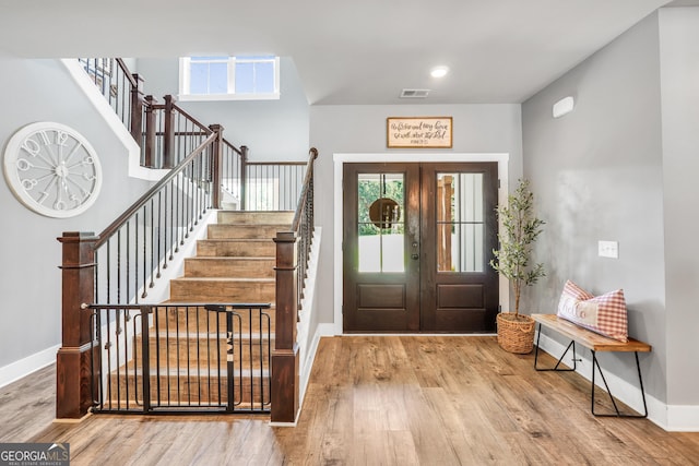 foyer with baseboards, stairs, visible vents, and wood finished floors