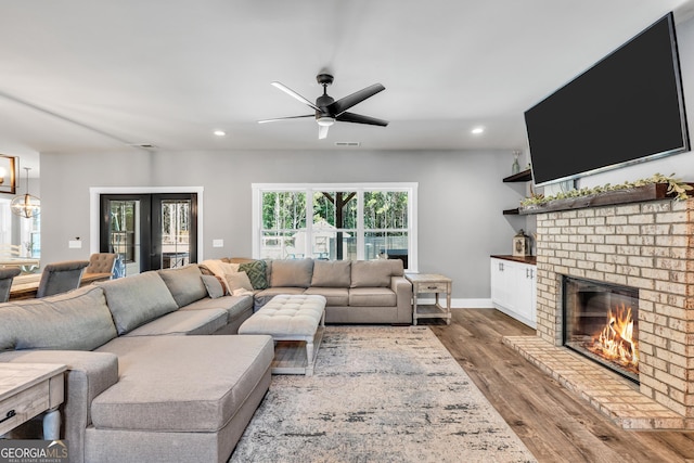 living room featuring french doors, a brick fireplace, wood finished floors, and recessed lighting