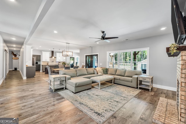 living area with recessed lighting, baseboards, visible vents, wood finished floors, and ceiling fan with notable chandelier