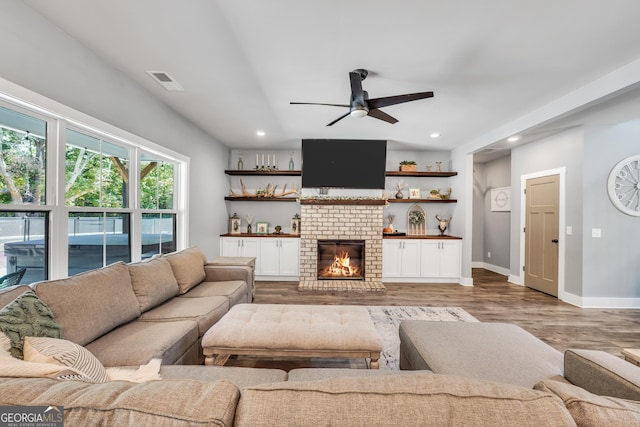 living room with baseboards, visible vents, wood finished floors, a brick fireplace, and recessed lighting