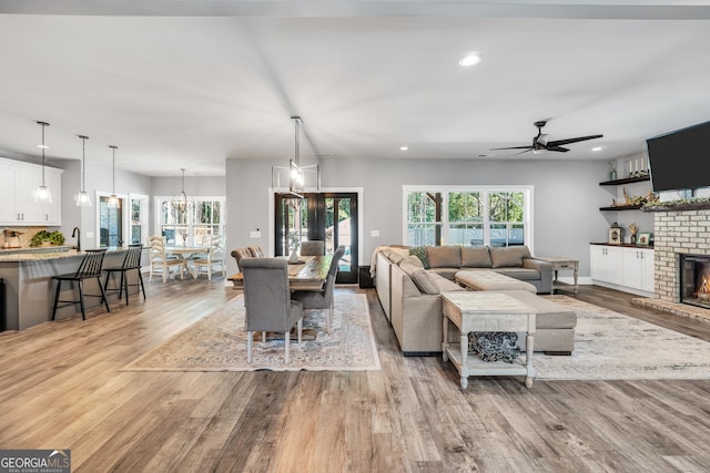 living room featuring light wood-style floors, ceiling fan, a fireplace, and recessed lighting