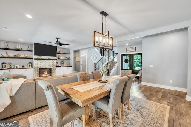 dining space featuring baseboards, stairs, light wood-style floors, a fireplace, and recessed lighting