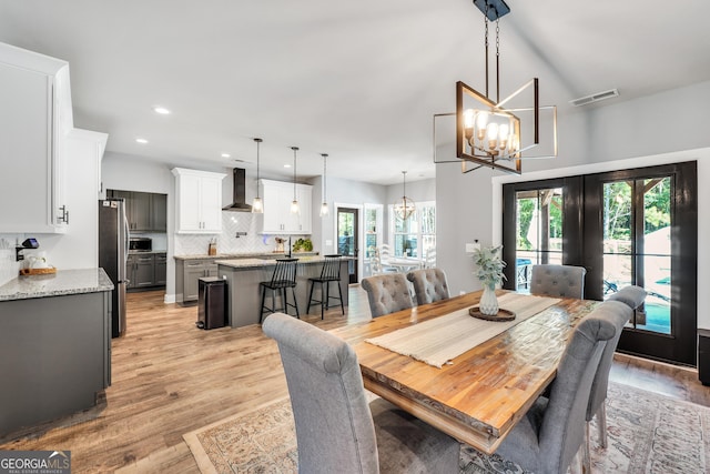 dining room featuring visible vents, light wood-style flooring, french doors, a notable chandelier, and recessed lighting