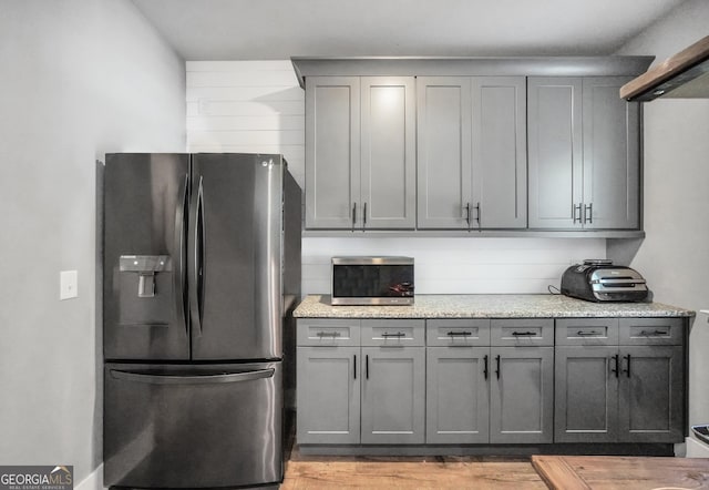 kitchen featuring light wood-style floors, light countertops, gray cabinets, and stainless steel fridge