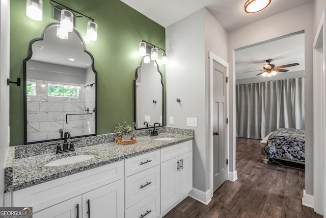 full bath with double vanity, wood finished floors, a stall shower, and a sink