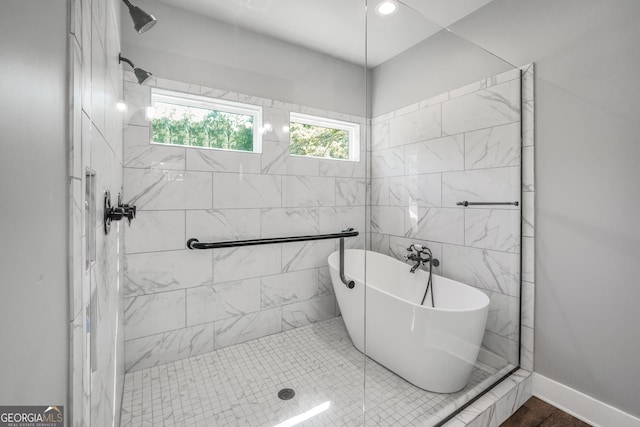 full bath with baseboards, a freestanding bath, and tiled shower