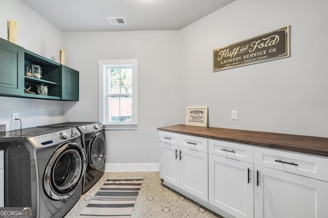 clothes washing area featuring visible vents, washer and clothes dryer, cabinet space, and baseboards