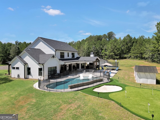 view of swimming pool featuring a patio, a storage shed, an outdoor structure, a lawn, and a fenced in pool