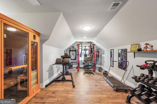 workout area featuring lofted ceiling, light wood-style flooring, visible vents, and baseboards