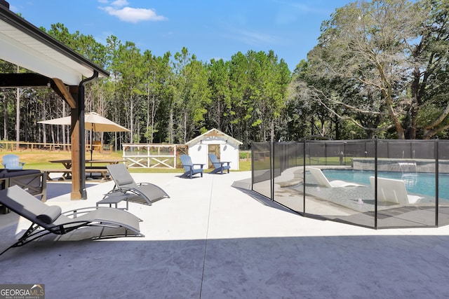 view of swimming pool with a patio area, fence, a fenced in pool, and an outdoor structure