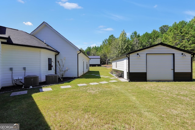 view of yard with an outbuilding, a detached garage, and central AC unit