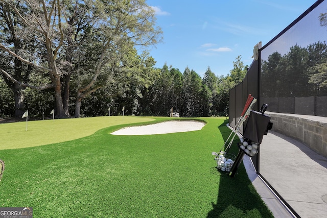 view of yard with view of golf course and fence