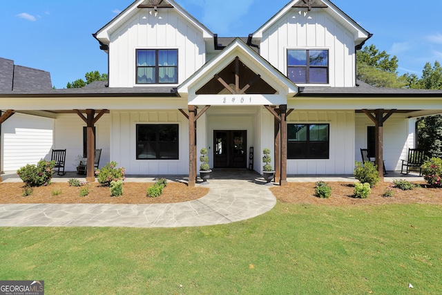 modern farmhouse with board and batten siding, a porch, a shingled roof, and a front lawn