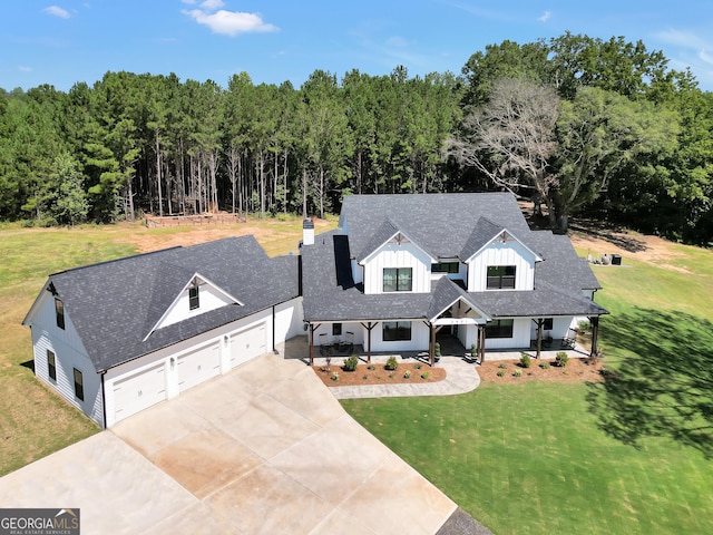 view of front of home featuring a porch, a front yard, a wooded view, and board and batten siding