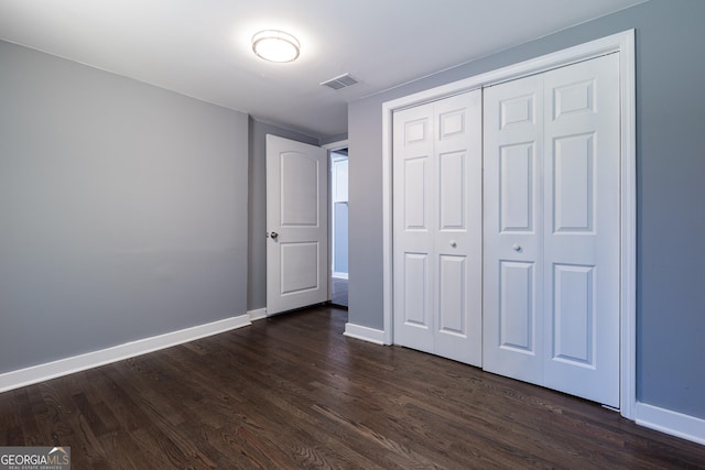 unfurnished bedroom with baseboards, visible vents, and dark wood-type flooring