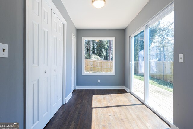 doorway to outside with dark wood-style floors and baseboards