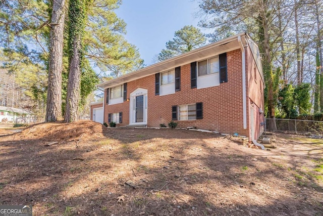 split foyer home featuring fence and brick siding