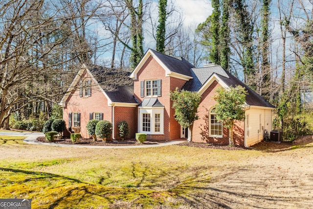 traditional-style house with cooling unit, brick siding, a chimney, and a front lawn