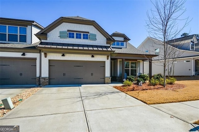 view of front facade featuring a garage, concrete driveway, stone siding, metal roof, and a standing seam roof