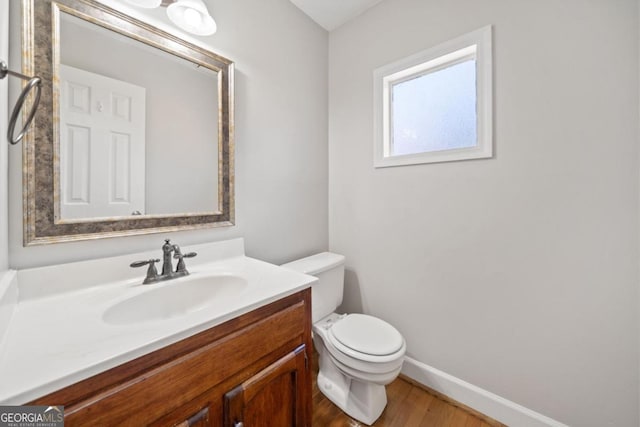 bathroom with baseboards, vanity, toilet, and wood finished floors