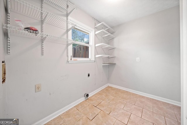 clothes washing area featuring baseboards, laundry area, tile patterned flooring, and hookup for an electric dryer