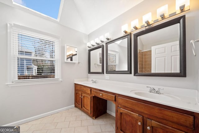 full bath with double vanity, tile patterned flooring, vaulted ceiling with skylight, and a sink