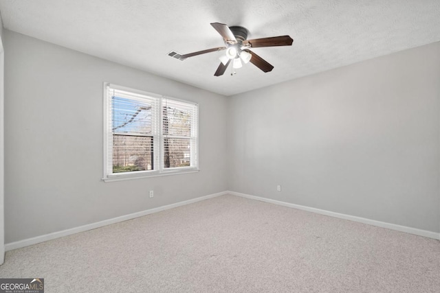 empty room with ceiling fan, carpet floors, visible vents, and baseboards