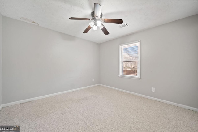 carpeted empty room with baseboards, visible vents, ceiling fan, and a textured ceiling