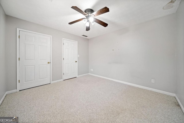 unfurnished bedroom with a ceiling fan, visible vents, baseboards, and carpet flooring