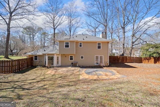 rear view of house with a yard, fence private yard, a patio, and a chimney