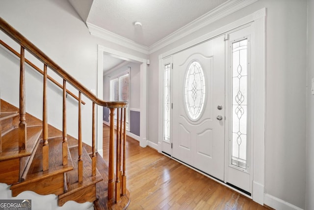 foyer with baseboards, stairway, ornamental molding, a textured ceiling, and light wood-style floors