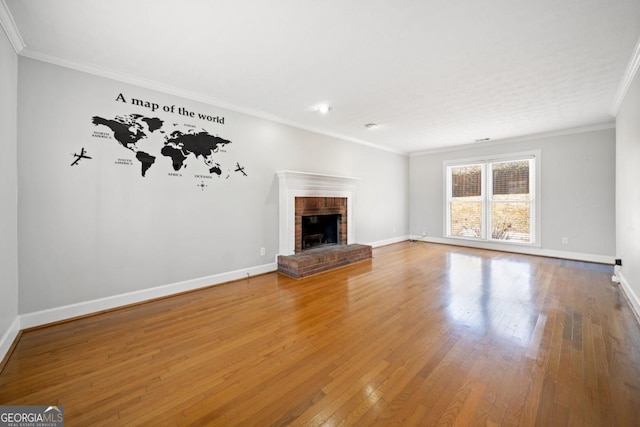 unfurnished living room featuring ornamental molding, a fireplace, baseboards, and hardwood / wood-style flooring