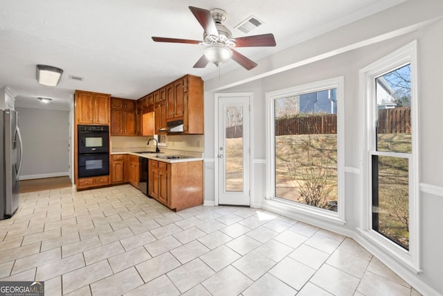 kitchen featuring a sink, visible vents, light countertops, black appliances, and brown cabinetry