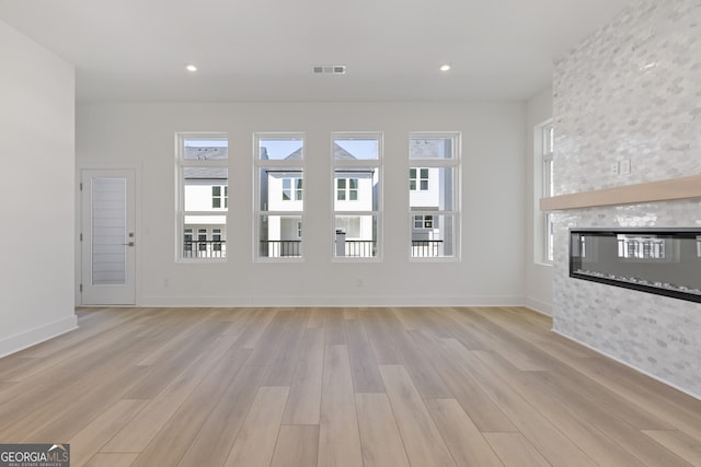 unfurnished living room with light wood-type flooring, a fireplace, visible vents, and recessed lighting