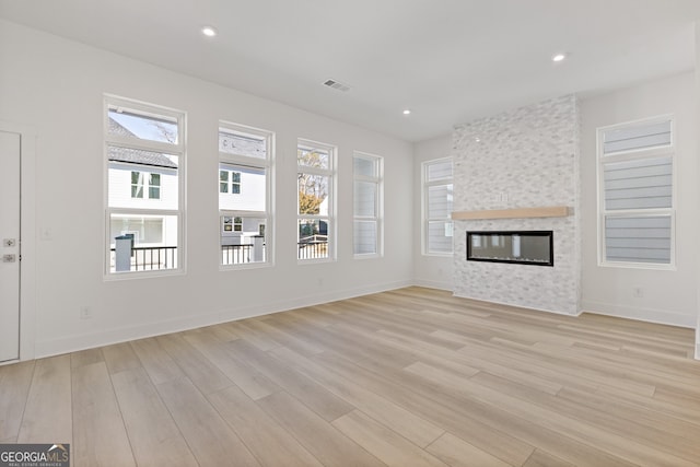 unfurnished living room with recessed lighting, light wood-type flooring, and a healthy amount of sunlight