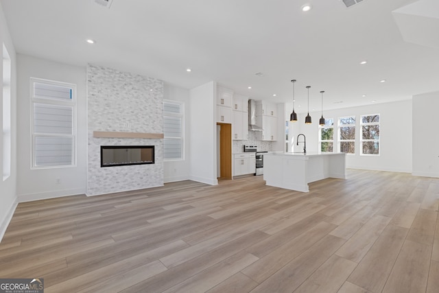 unfurnished living room featuring recessed lighting, light wood-style flooring, a sink, a tile fireplace, and baseboards