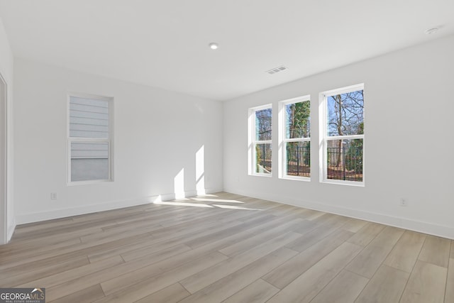 unfurnished room featuring light wood-style flooring, visible vents, and baseboards