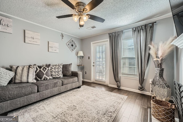 living room with a textured ceiling, a ceiling fan, crown molding, and wood finished floors