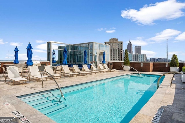 community pool with a patio area and a view of city