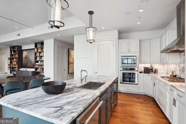 kitchen featuring a sink, stainless steel appliances, white cabinets, and wall chimney range hood