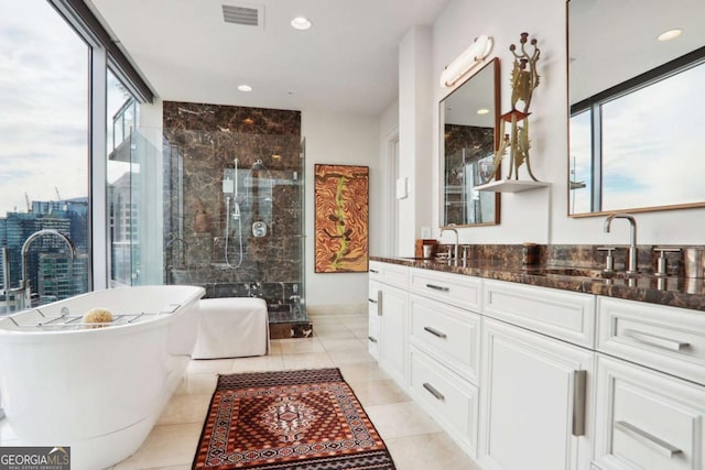 bathroom with visible vents, a sink, a shower stall, double vanity, and a soaking tub