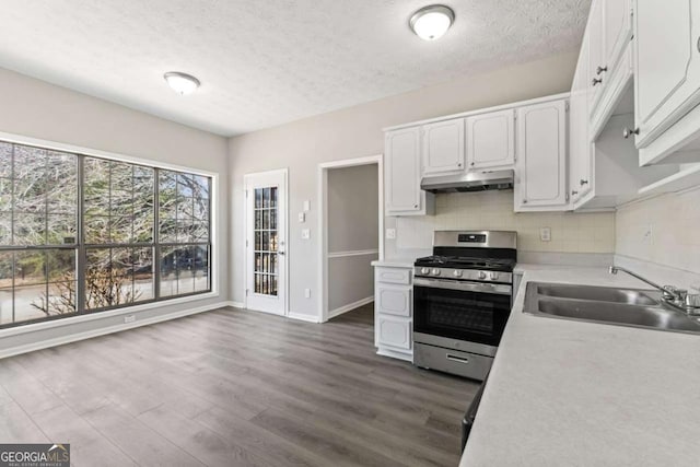 kitchen featuring stainless steel gas range, light countertops, under cabinet range hood, white cabinetry, and a sink