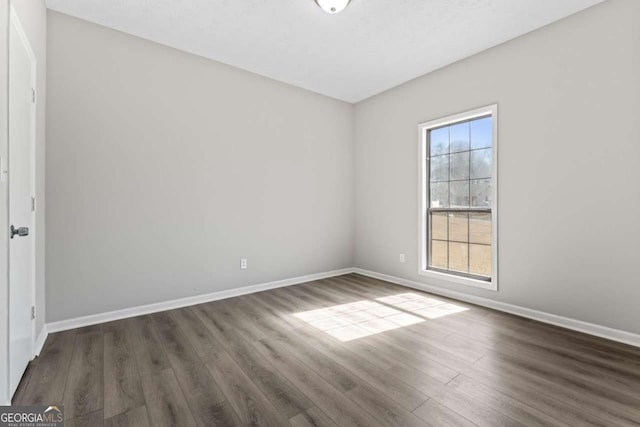 spare room with dark wood-type flooring and baseboards