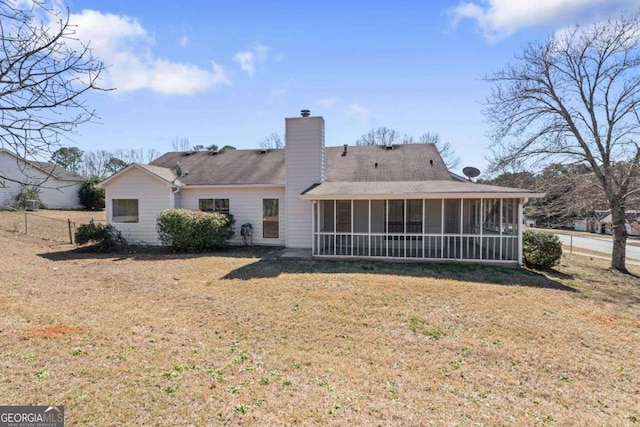 back of property with a sunroom, a lawn, and a chimney