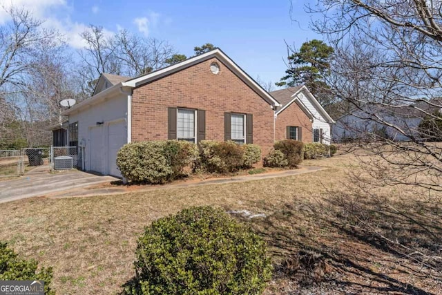 view of side of property with an attached garage, brick siding, fence, a yard, and driveway