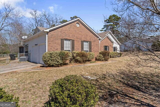 view of property exterior featuring a gate, fence, driveway, a garage, and brick siding