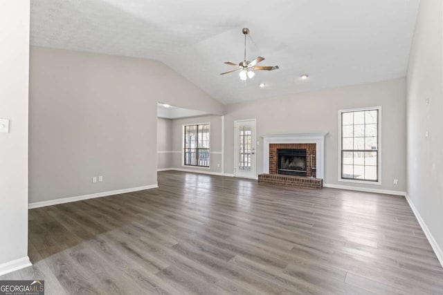 unfurnished living room with a fireplace, wood finished floors, a ceiling fan, baseboards, and vaulted ceiling