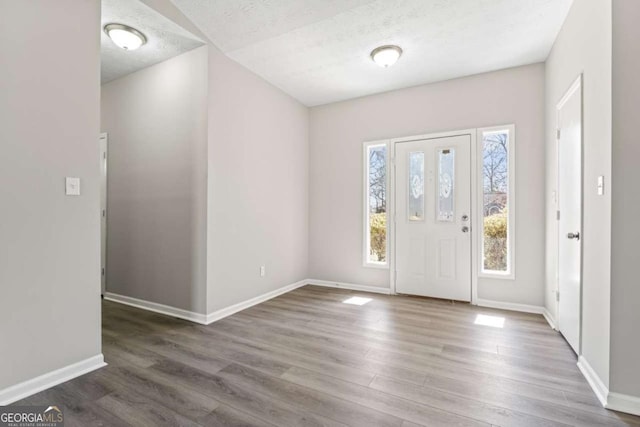 entrance foyer featuring a textured ceiling, wood finished floors, and baseboards